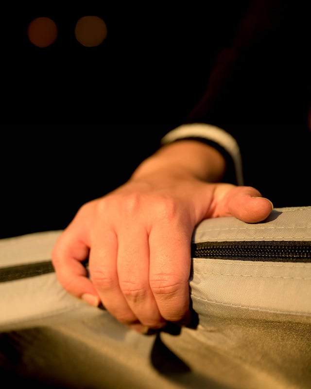 Primo piano di una mano che afferra il bordo del materasso della tenda da tetto Front Runner Dometic Feather‑Lite II, con trama del tessuto e cerniera visibili.