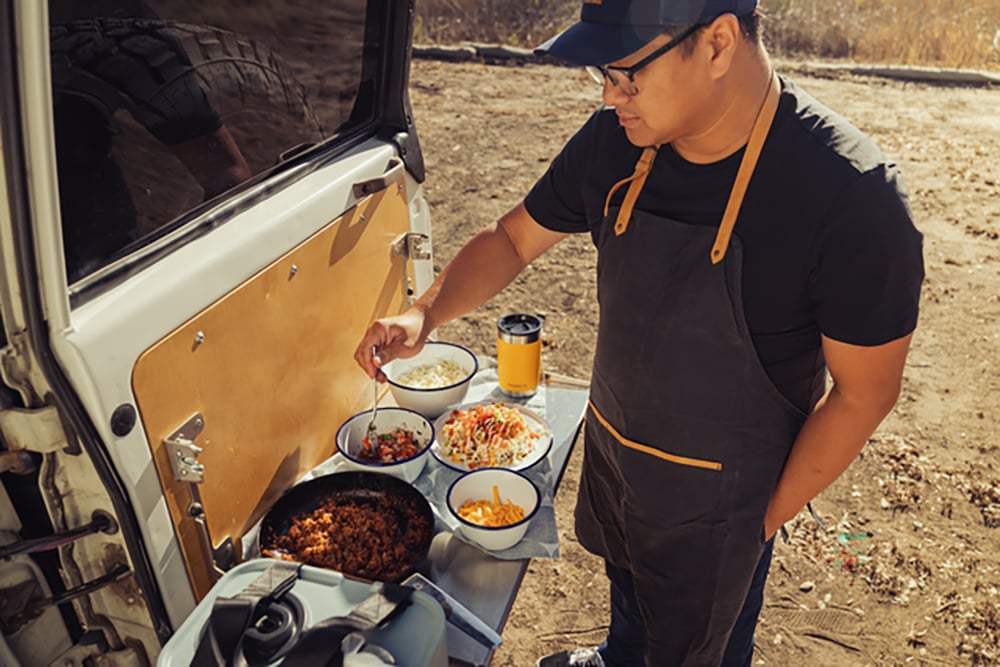 A man cooking from the back of his truck.