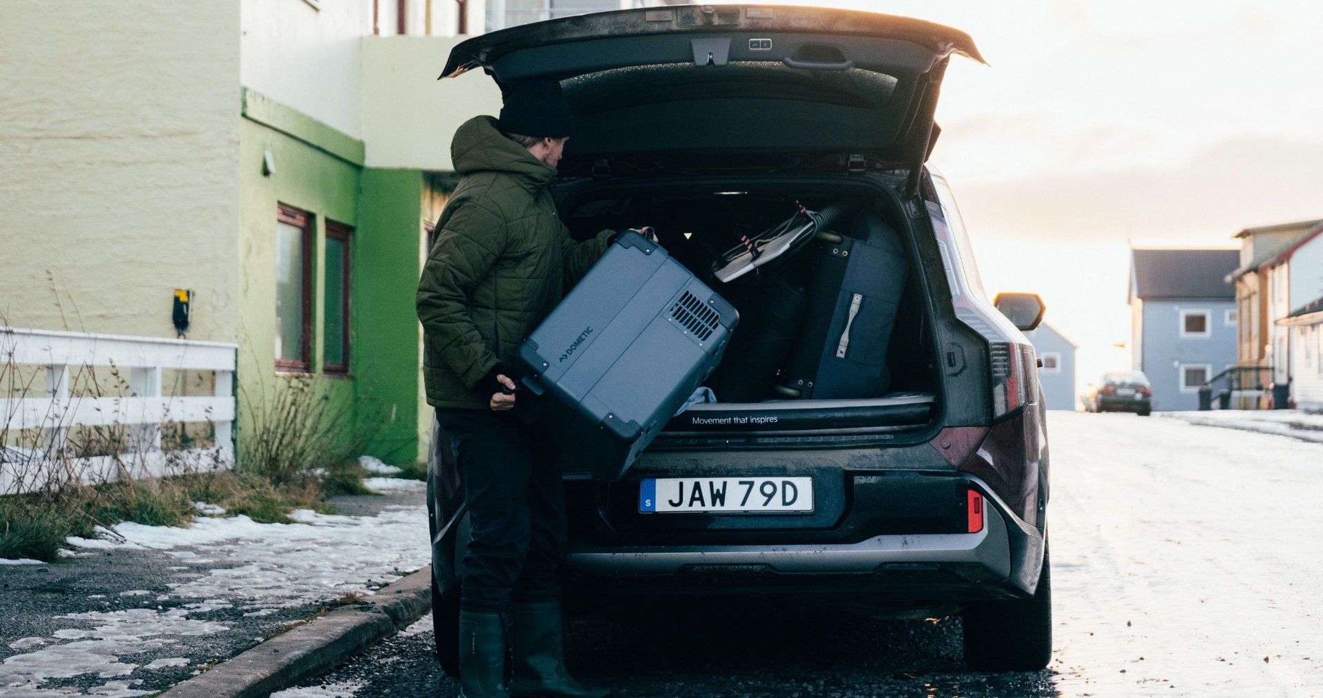A person loading a Dometic cooler into the back of a SUV packing the car for an adventure.