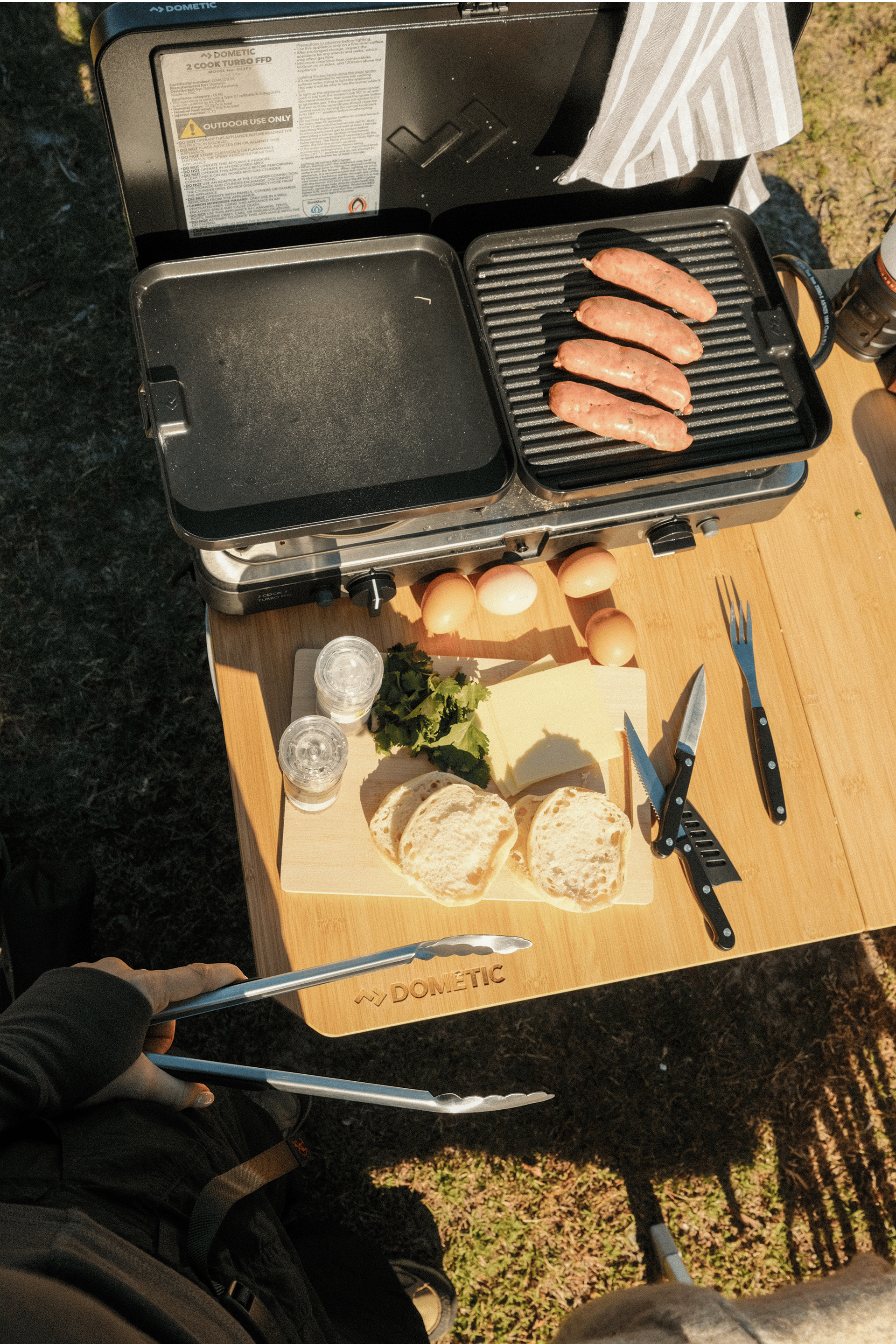 Enjoying camp cooking with the Dometic 2 Cook Turbo FFD, Breanna Hurst prepares a meal during her North Stradbroke Island camping adventure.