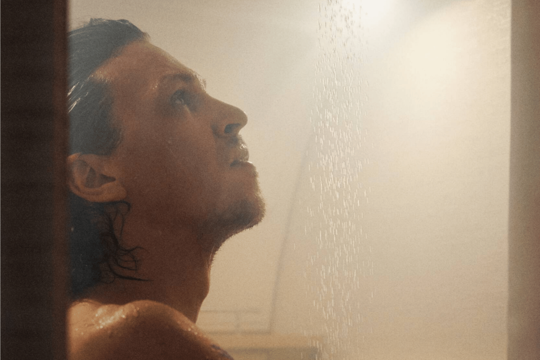 Man in rv shower looking up at shower head.