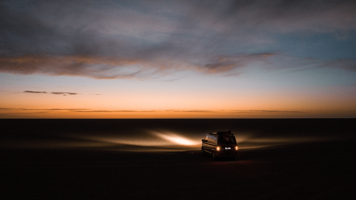 Pick-up équipé d’une galerie de toit, d’une barre lumineuse LED, de plaques de désensablage et de boîtes de rangement roulant dans des conditions tout-terrain poussiéreuses