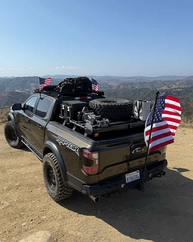 Black truck with bed rack system and USA flag.
