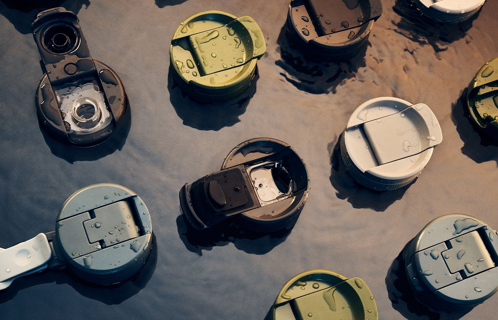 Olika lock till isolerade dryckesbehållare med vattendroppar som flyter i grunt vatten utomhus.