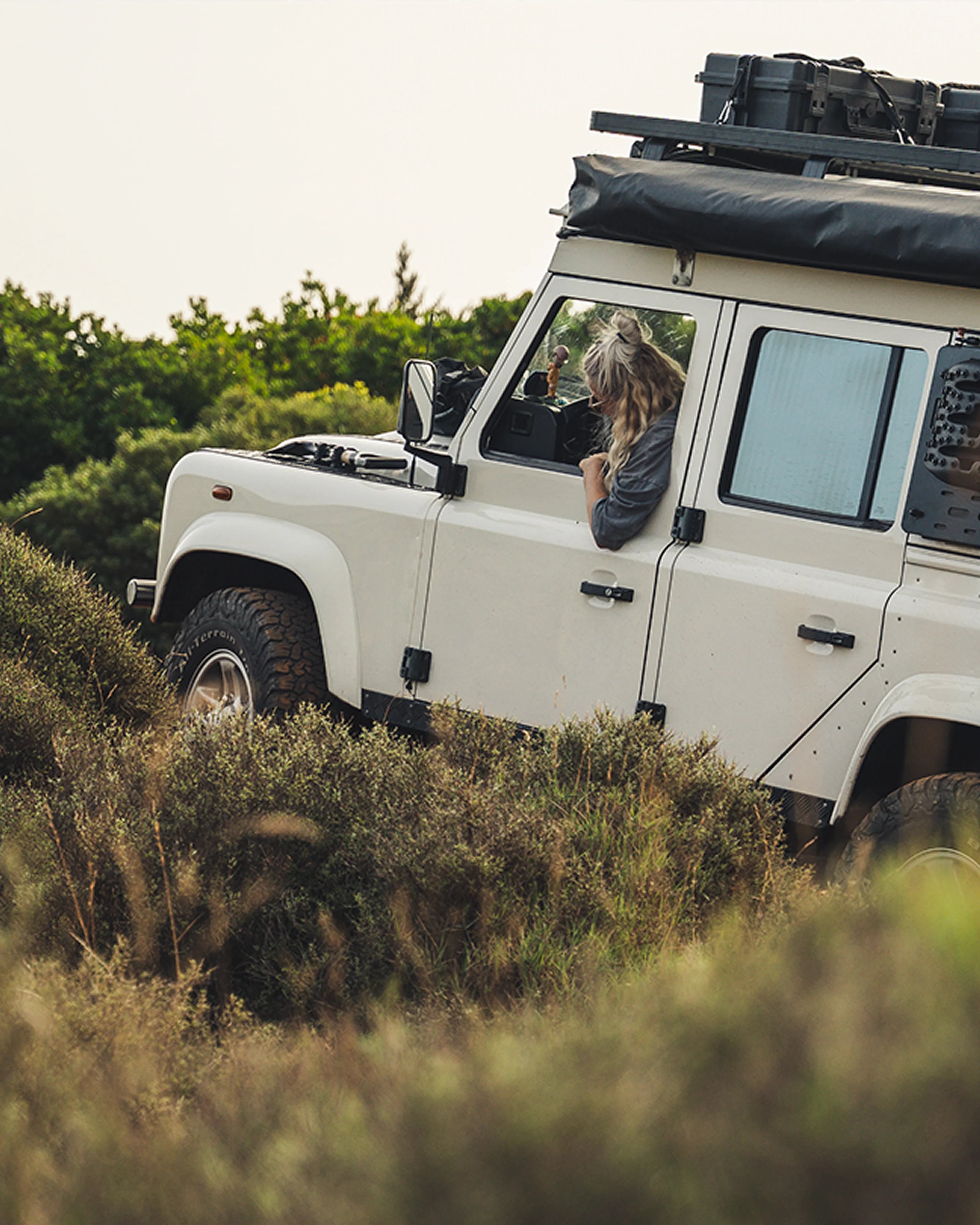 Front Runner Dometic Slimline II roof rack mounted on Land Rover Defender, carrying storage boxes and gear for overland travel