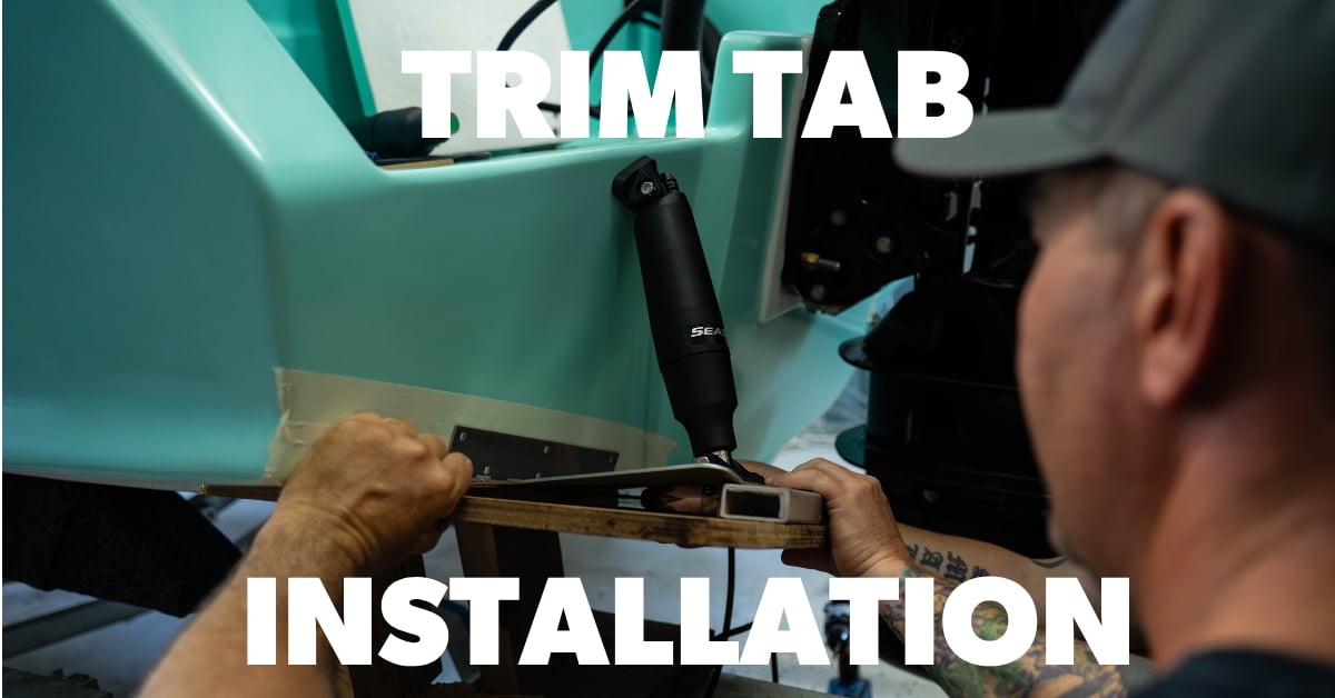 Person installing trim tabs on a boat with white text overlay saying Trim Tab Installation