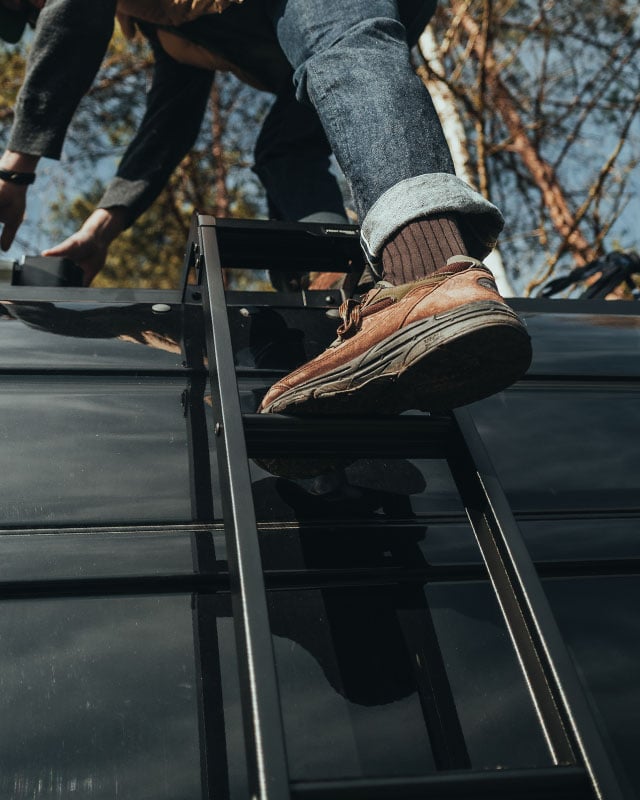 Person climbing vehicle-mounted ladder to access roof rack, durable rear ladder for overland and outdoor vehicle setups