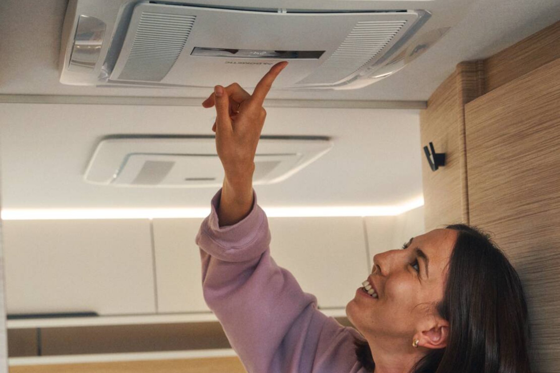 Woman interacting with an RV air conditioner unit.