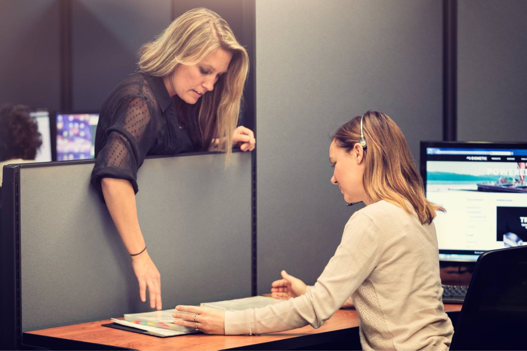 Corporate Support employees reviewing training guide in cubicle desk area.