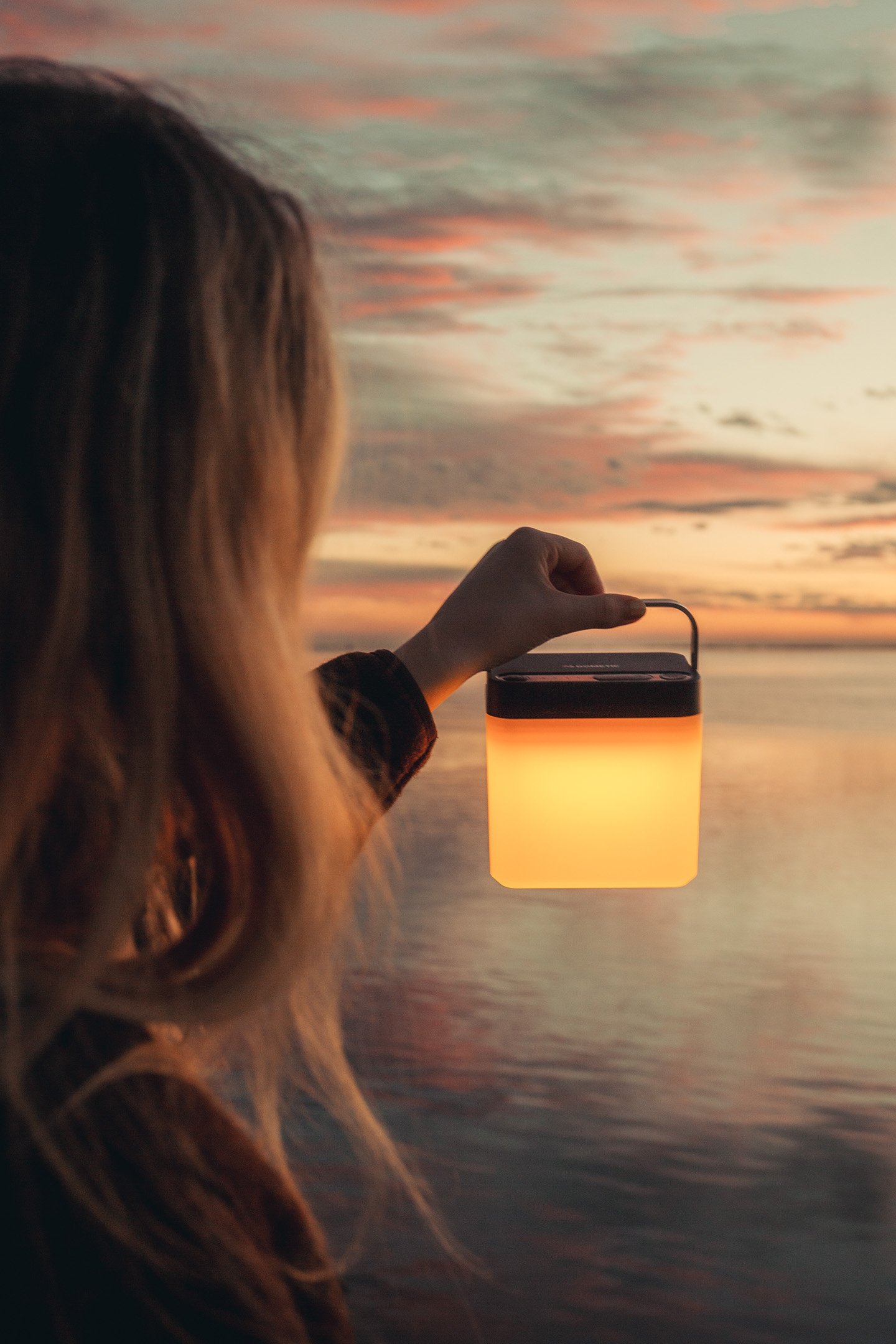 Woman holding the Dometic GO Area Camp Light in a sunset setting