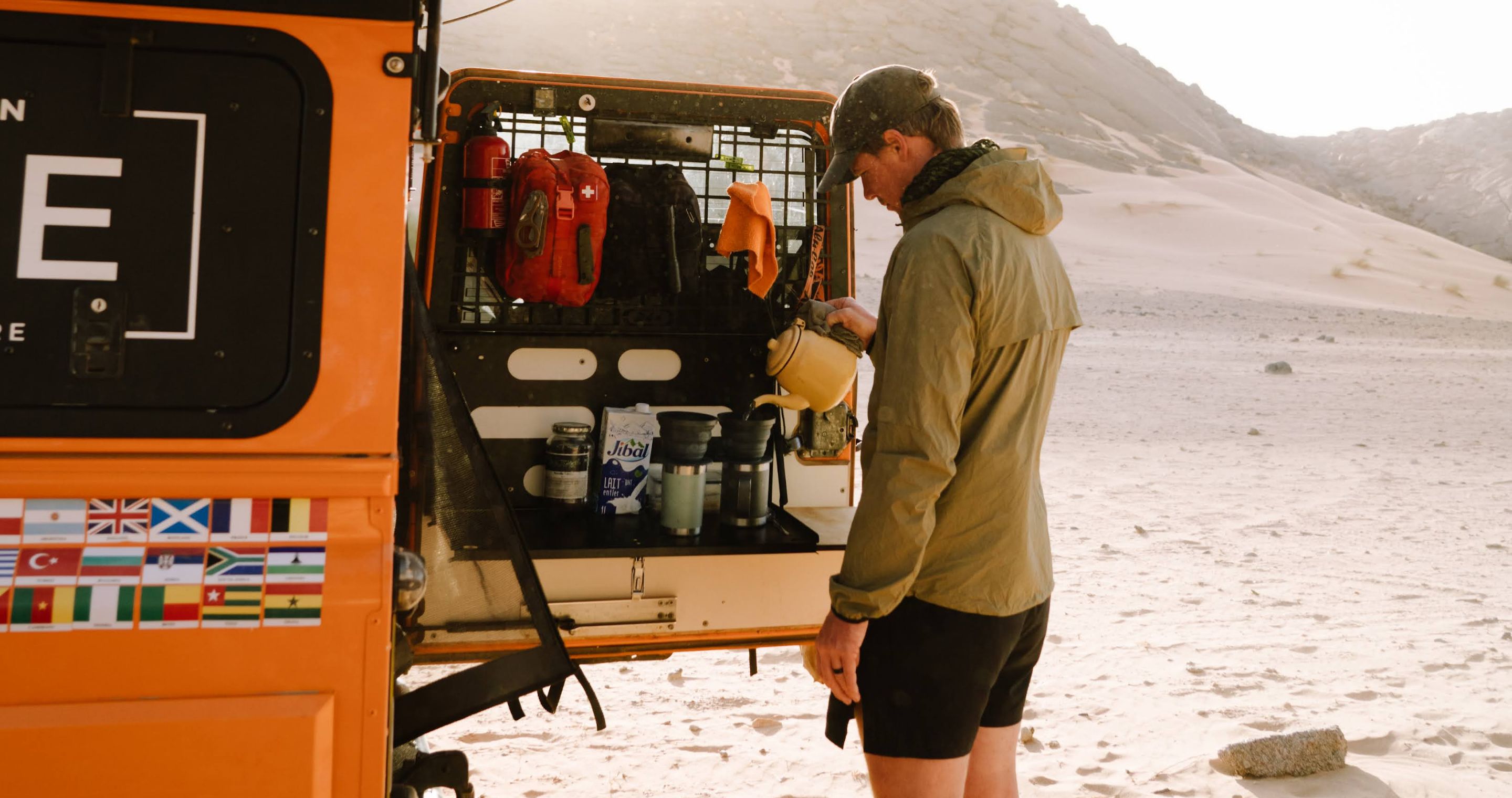 Person standing at back of car pouring coffee