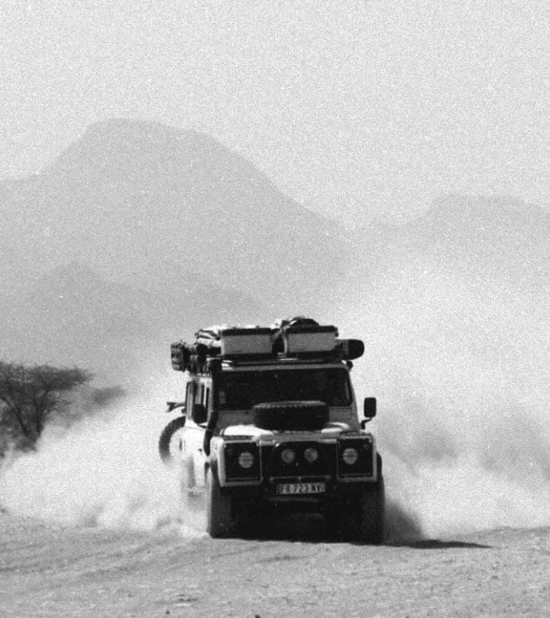 Black and white car driving in dust