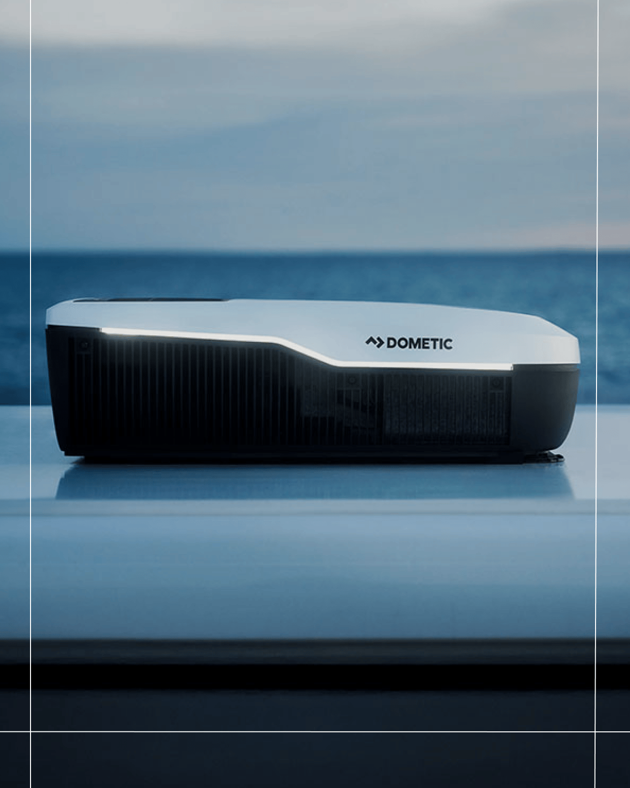 Aire acondicionado Dometic FreshJet montado en el techo de un vehículo con vistas al mar, con iluminación ambiental integrada