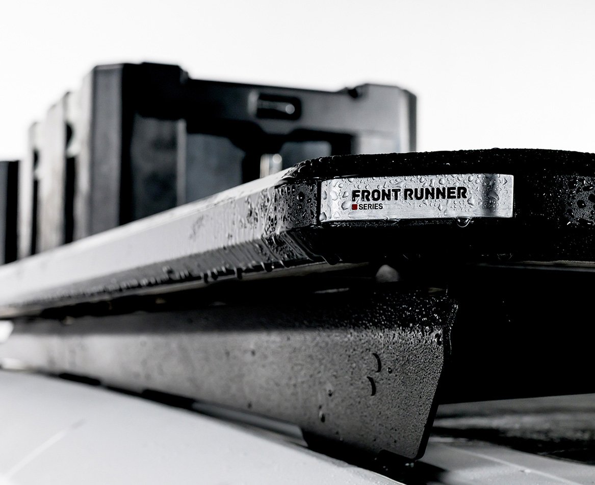 Close-up of a Slimline 3 roof rack with water droplets, highlighting the low-profile side rail design and mounted storage boxes