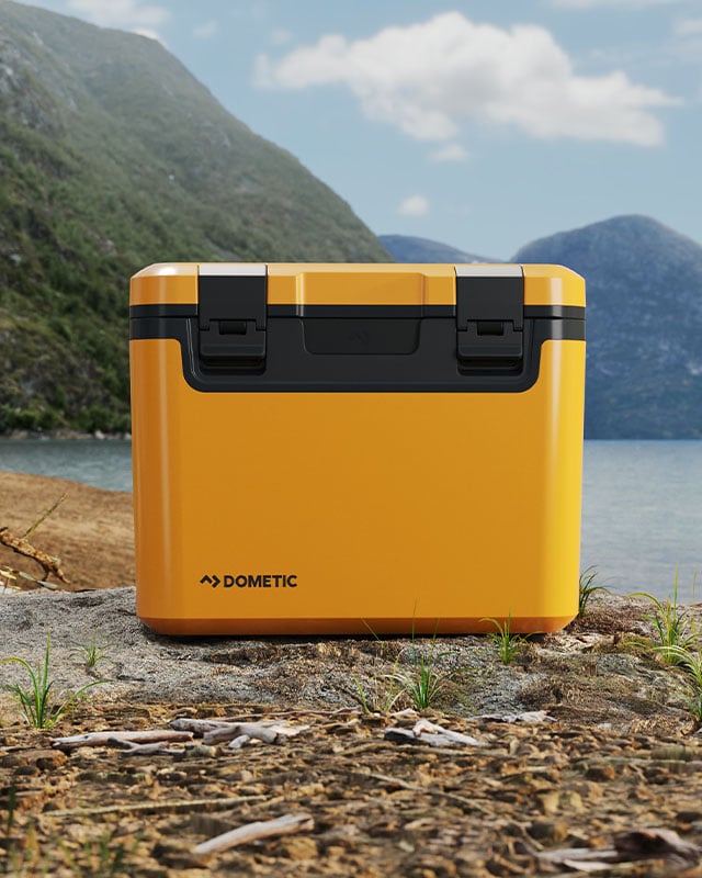 Dometic Recon passive cooler placed outdoors by a lake, durable hard cooler designed for camping and outdoor use