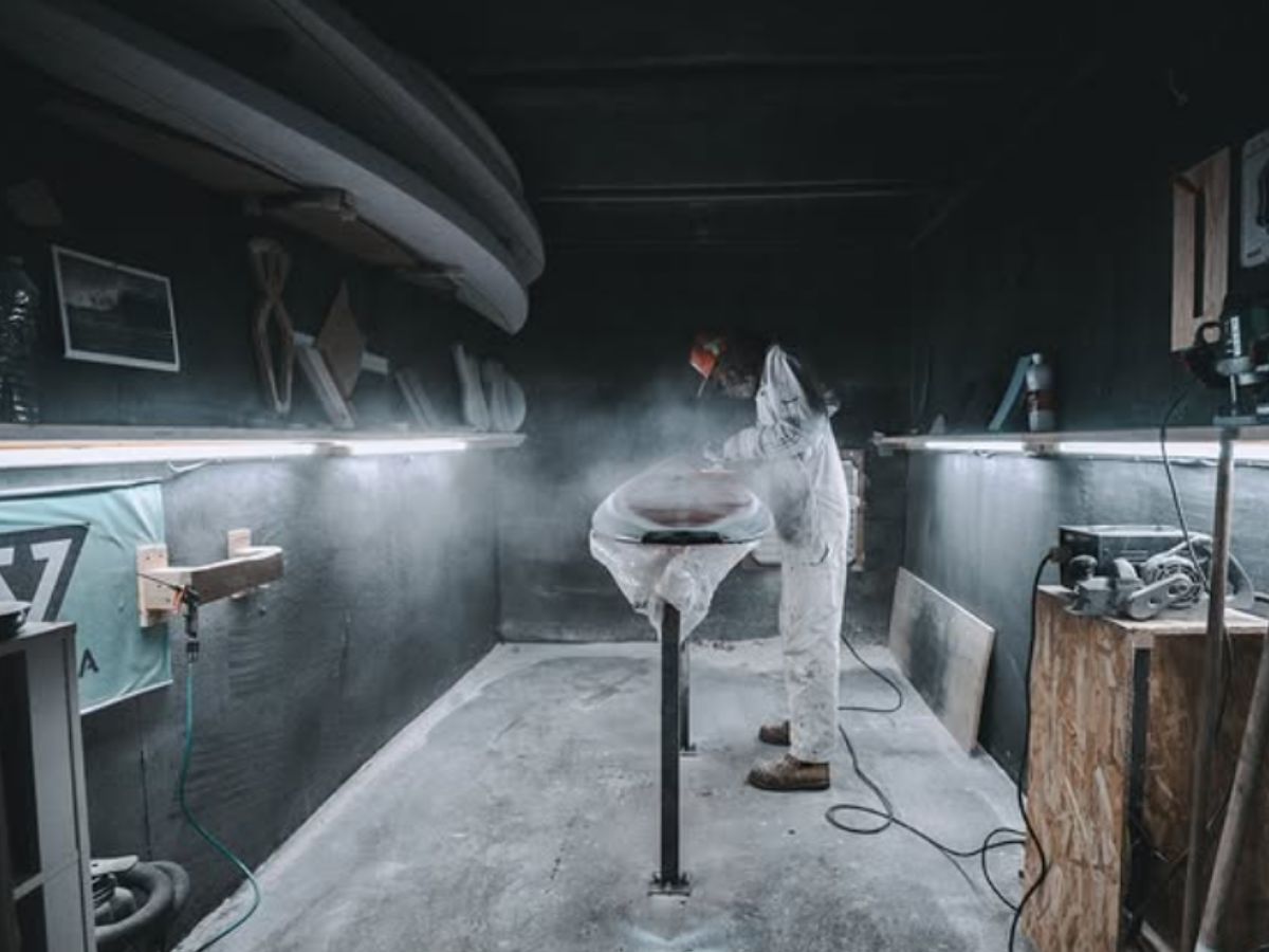 Wide shot of a man shaping a surfboard