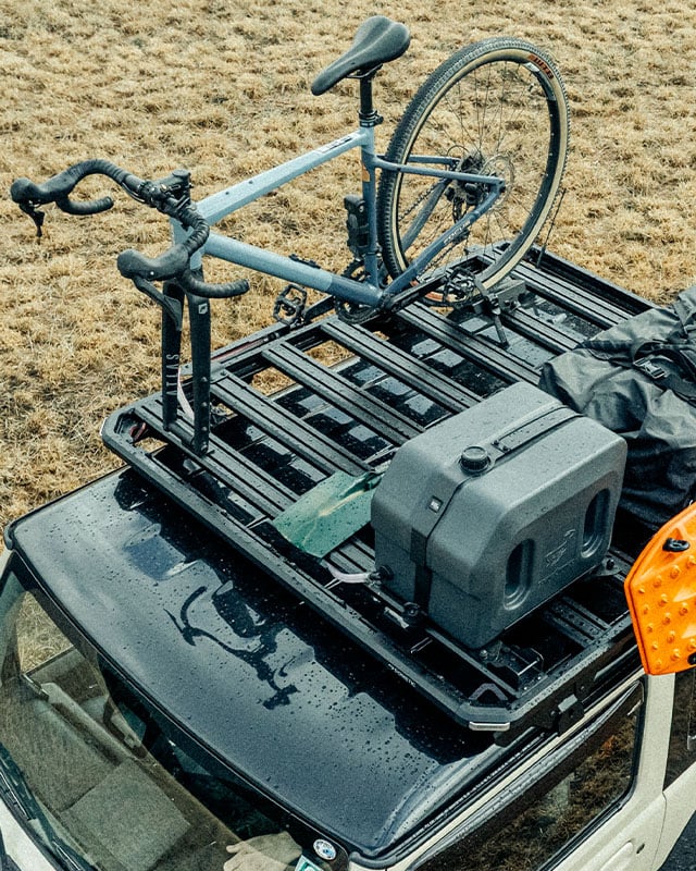 Slimline 3 roof rack with a roof-mounted bike carrier, water tank, recovery board and cargo bag, showcasing accessory compatibility for outdoor adventures