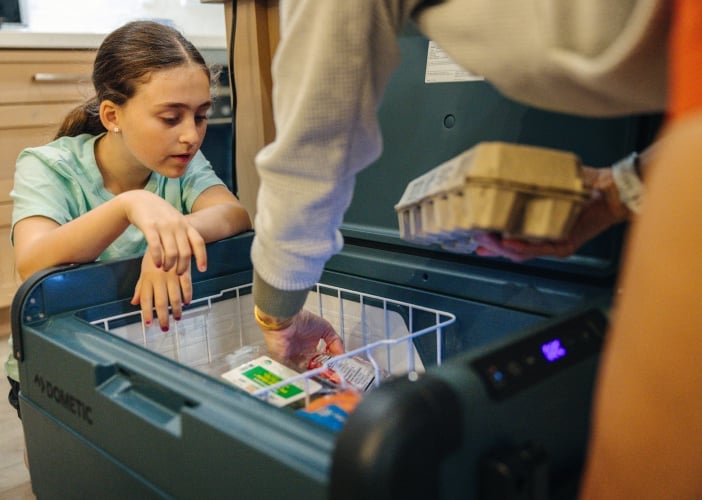 Een meisje kijkt naar een koelbox die wordt ingepakt.