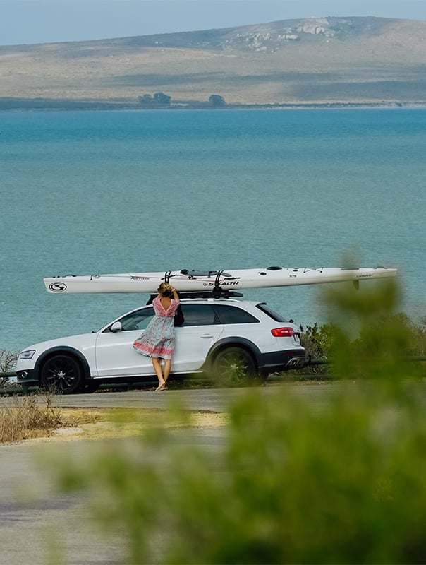 A car parked by the beach with a kayak on the roof