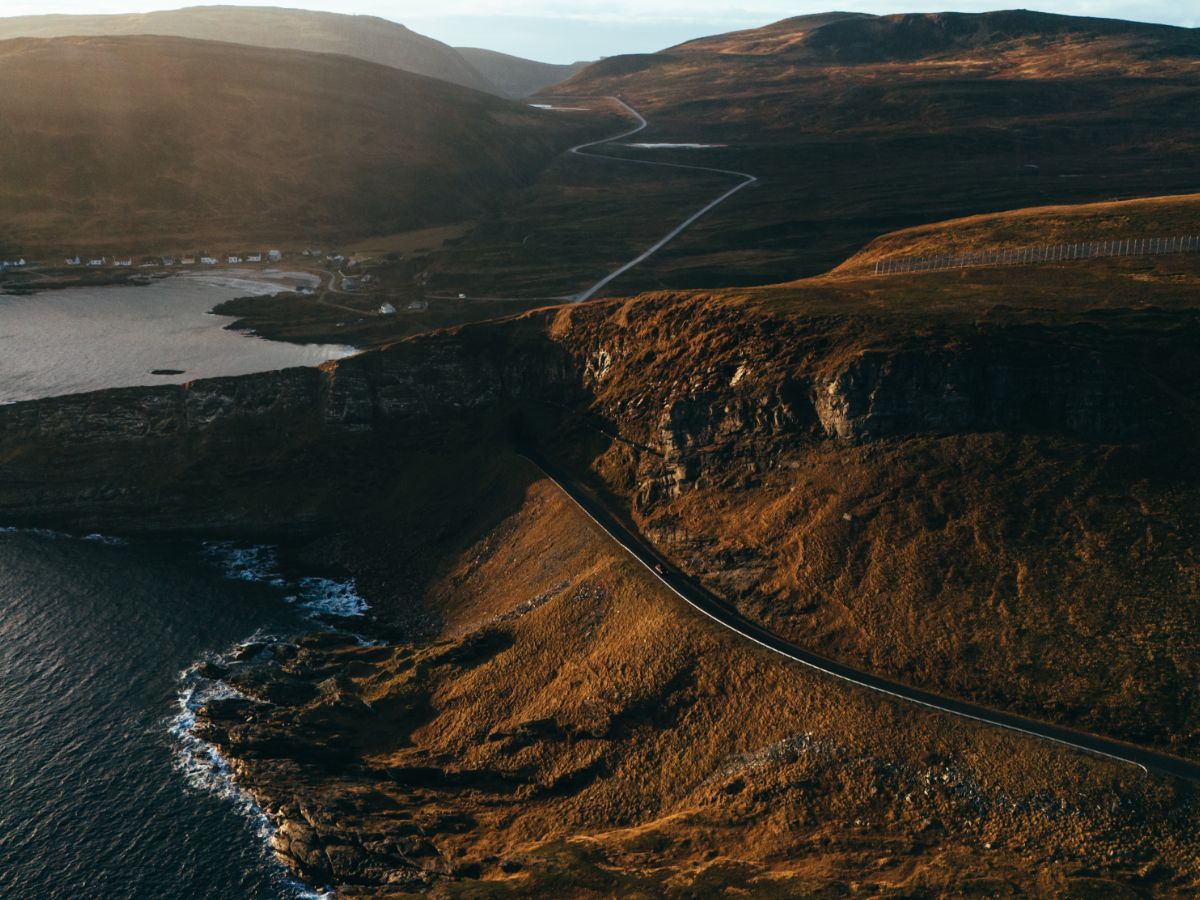 Drone shot image of a road through the coastline and mountains