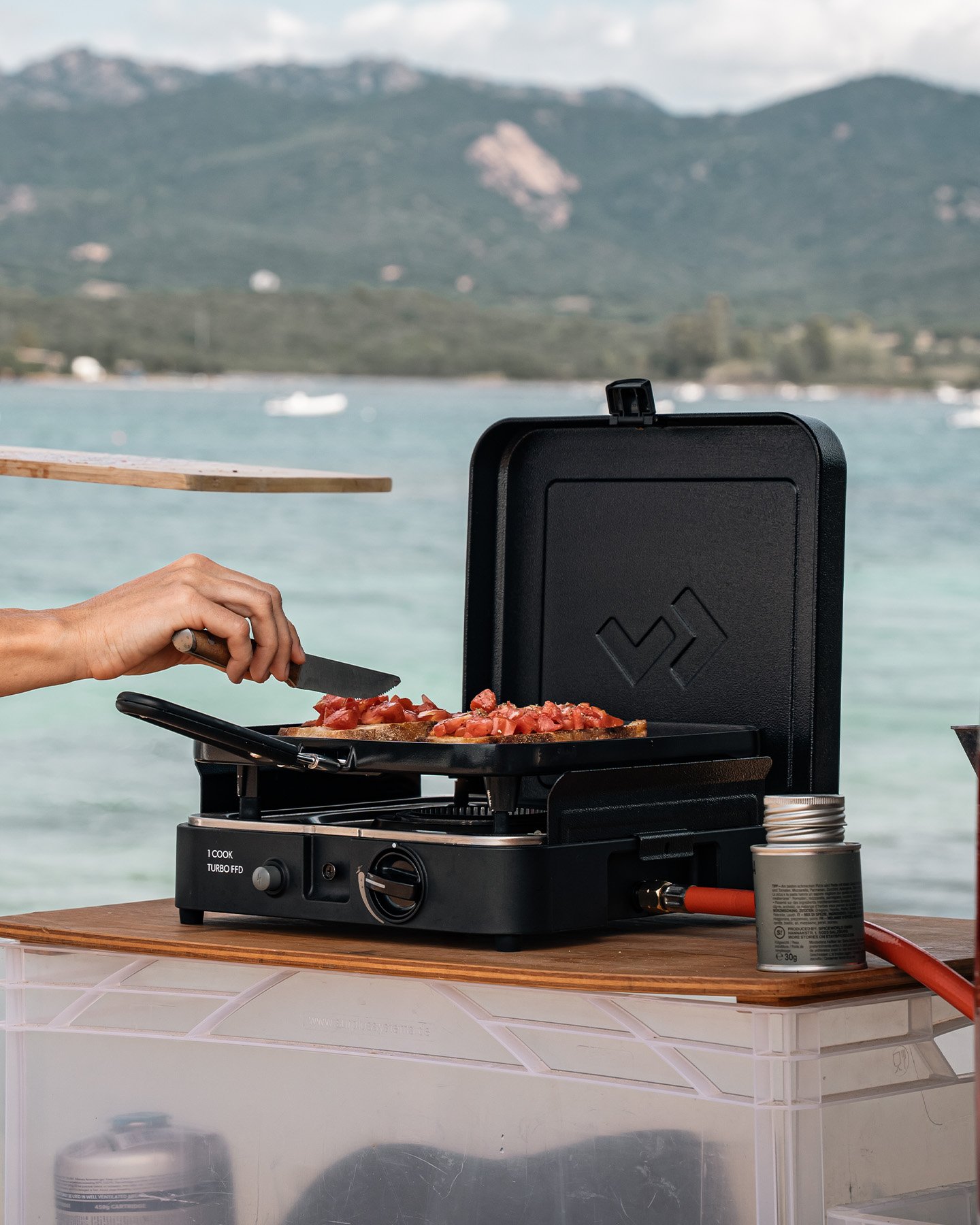 Cocina de gas portátil CADAC 1 Cook Turbo FFD Stove Flat Plate utilizada junto al agua, con plancha para camping y cocina al aire libre