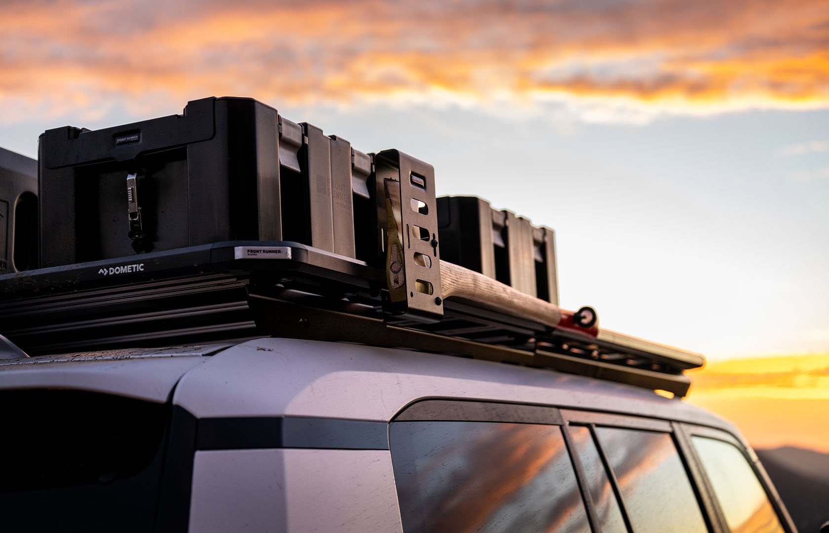 Slimline 3 roof rack fitted with storage boxes, a shovel mount and utility accessories on a vehicle at sunset