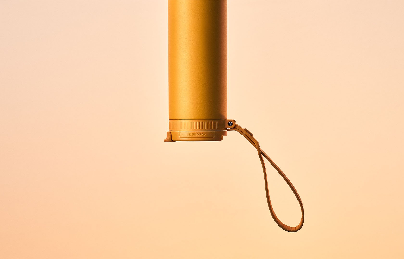Gul isolerad termoflaska som hänger upp och ner med rem mot en varm gradientbakgrund.