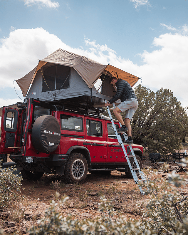 Man climbing ladder into roof top tent