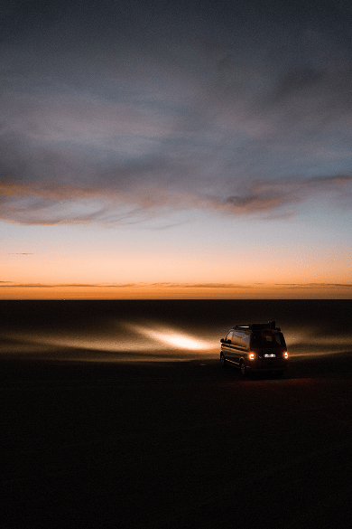 Pick-up équipé d’une galerie de toit, d’une barre lumineuse LED, de plaques de désensablage et de boîtes de rangement roulant dans des conditions tout-terrain poussiéreuses