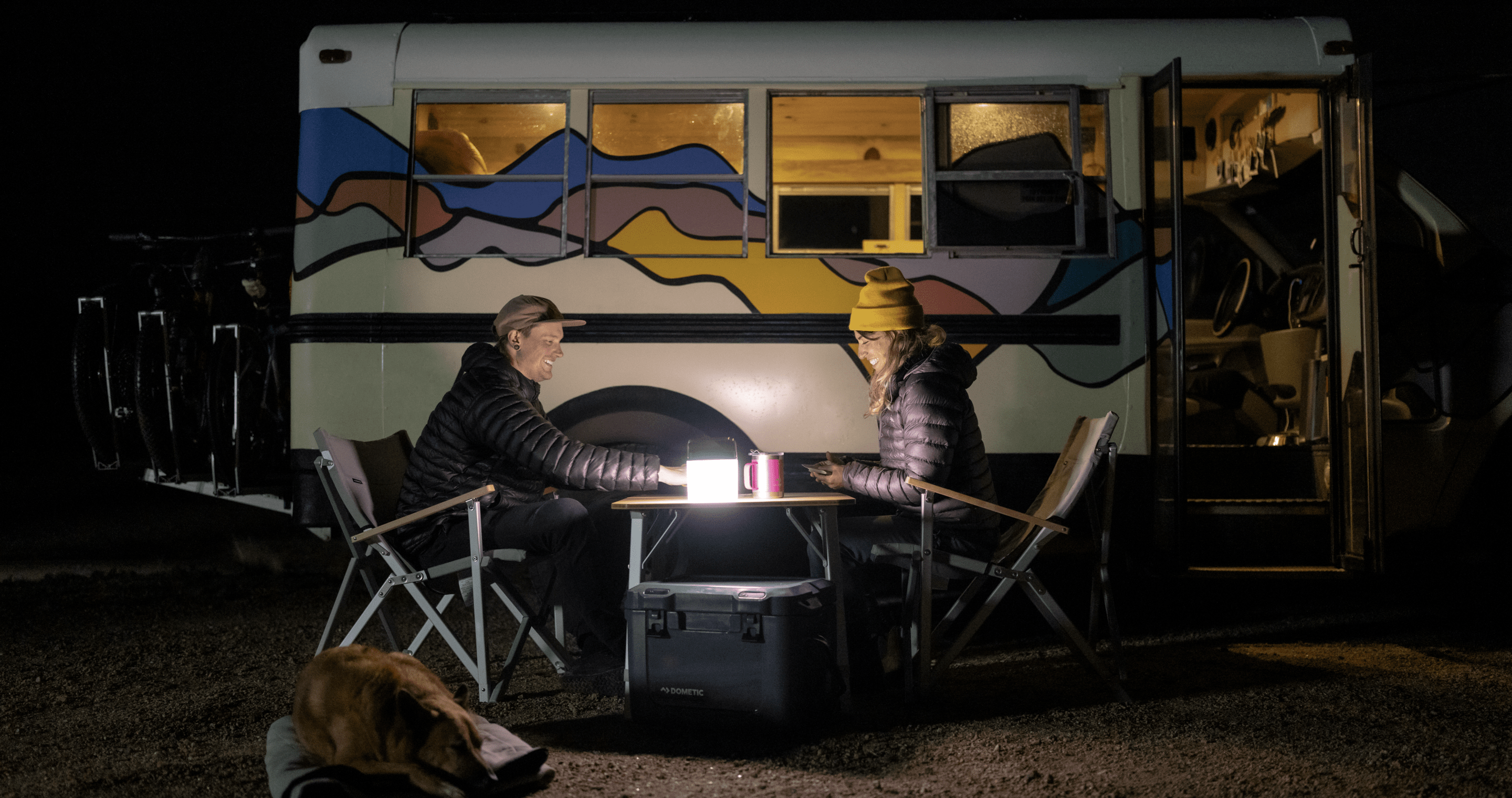 Couple sitting at table camping at night