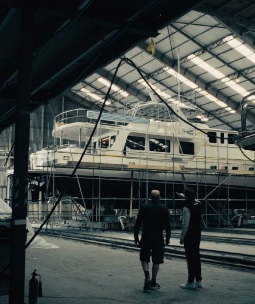 Two people looking at a boat under construction