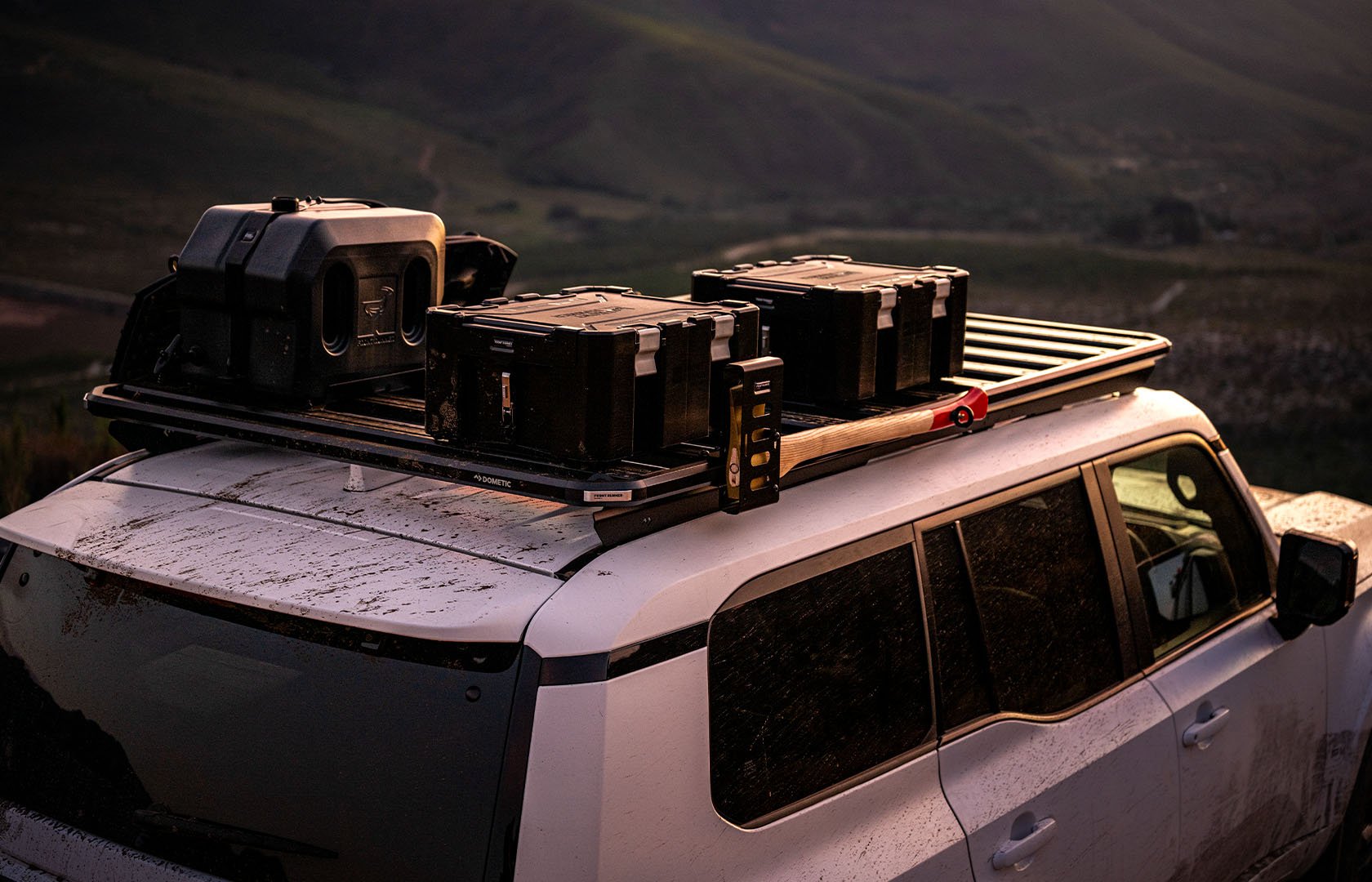 Slimline 3 roof rack carrying storage boxes, recovery gear and utility accessories on a vehicle in a mountain landscape
