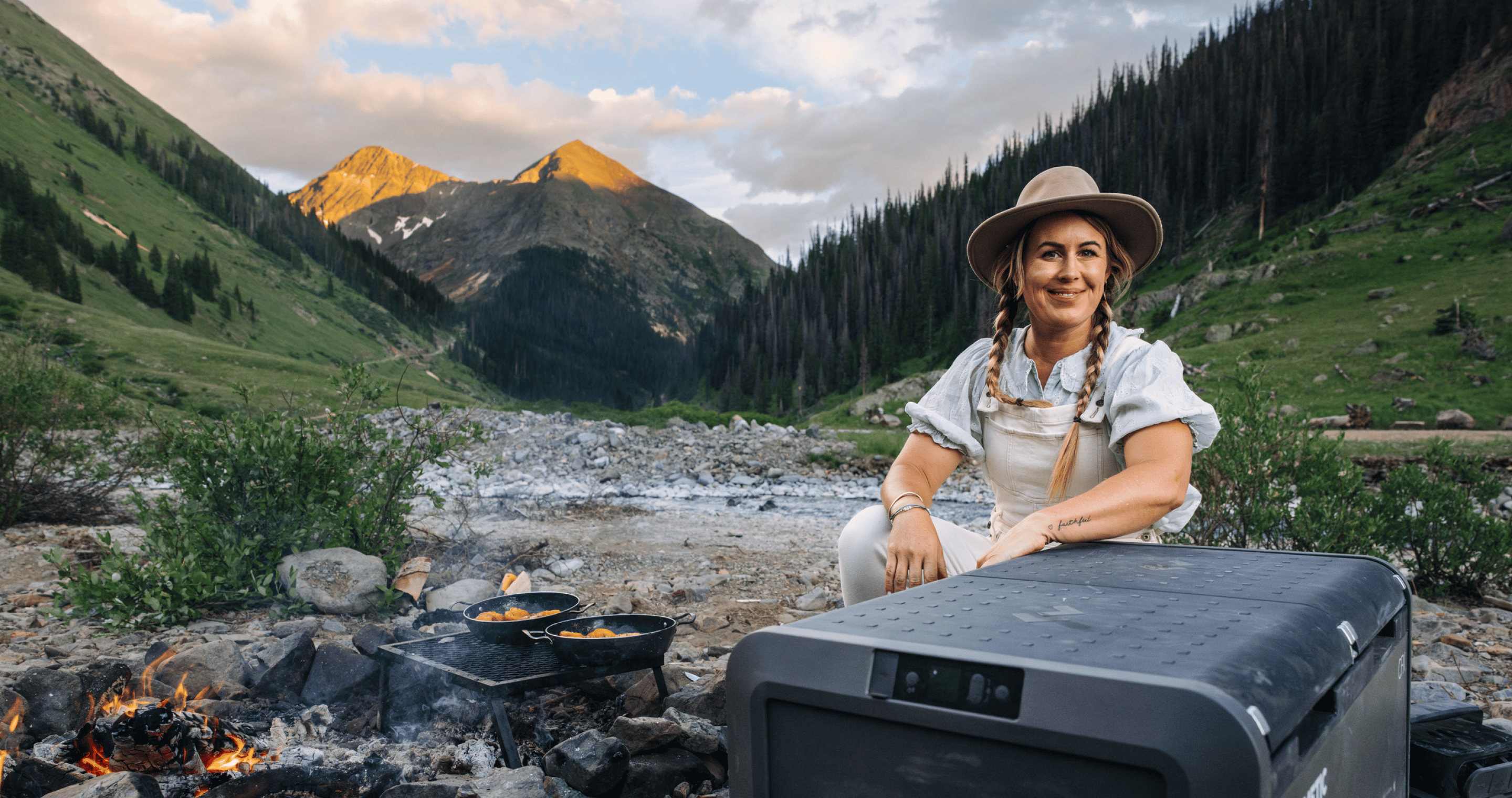 woman at campsite with cooler in foreground and mountains in background