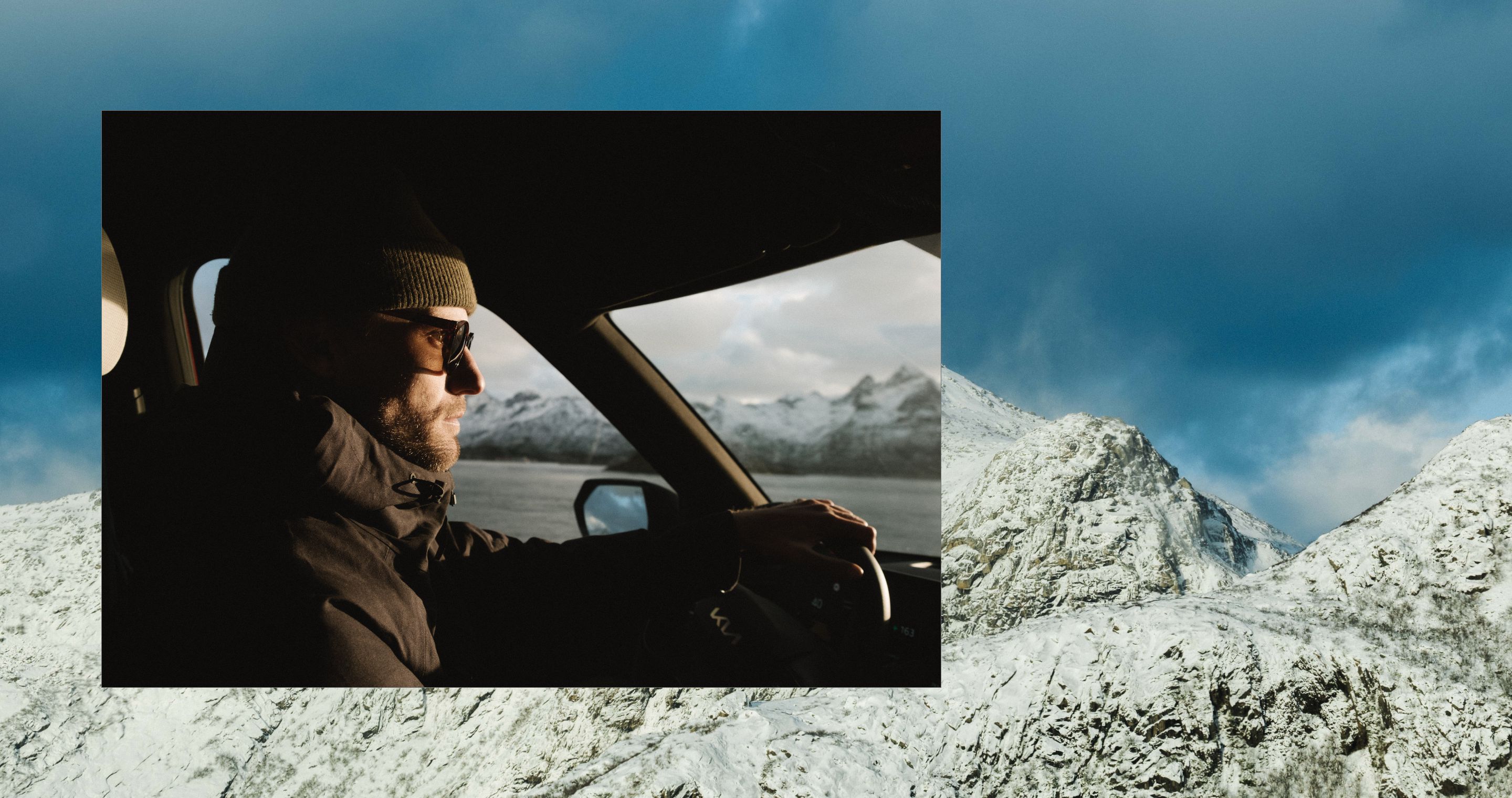 A person driving a vehicle with snowy mountains in the distance