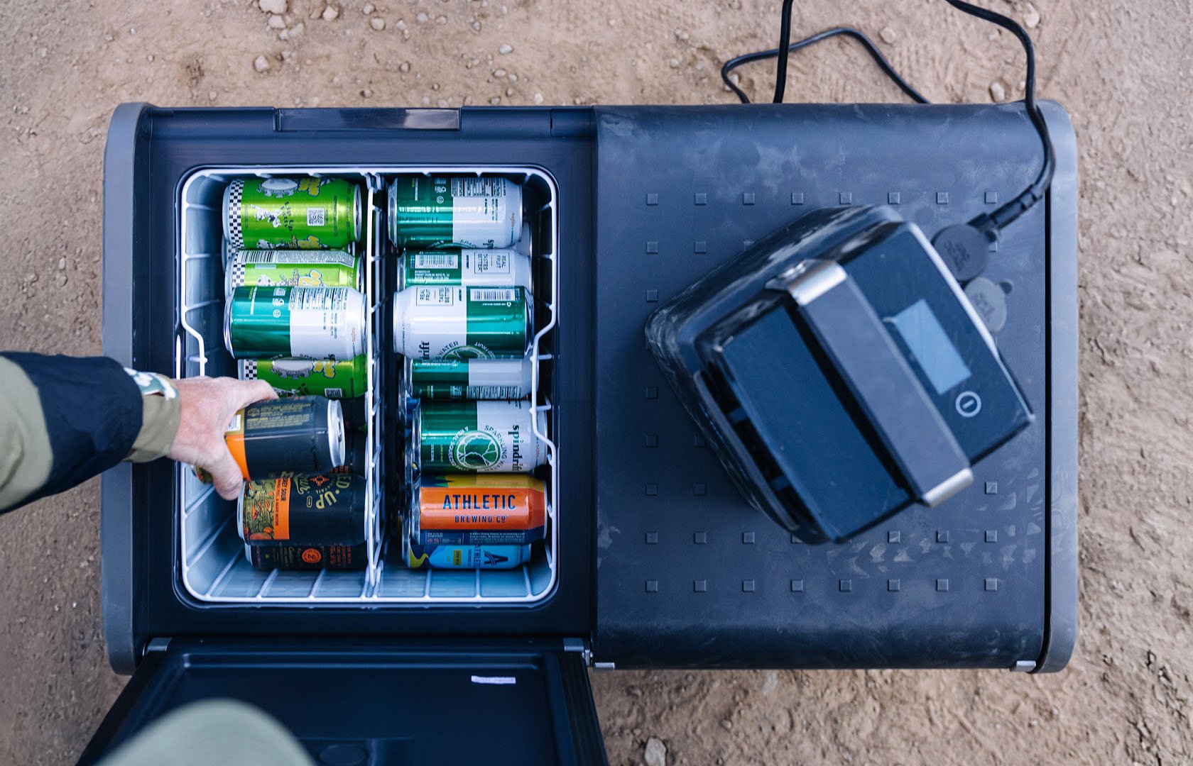 Geöffnete Dometic CFX5 Kompressor-Kühlbox mit Getränkedosen, tragbare elektrische Kühlbox in Draufsicht und am Strom angeschlossen