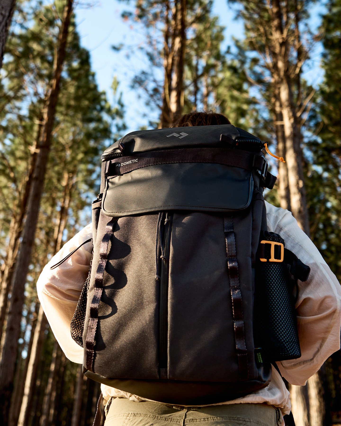 Person med stor outdoorryggsäck i skog, slitstark utrustning för vandring och äventyr