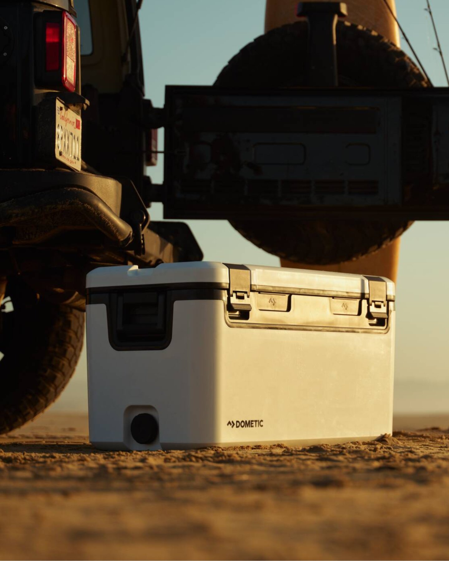 Recon cooler in white at sunset, beneath a car on the ground. 