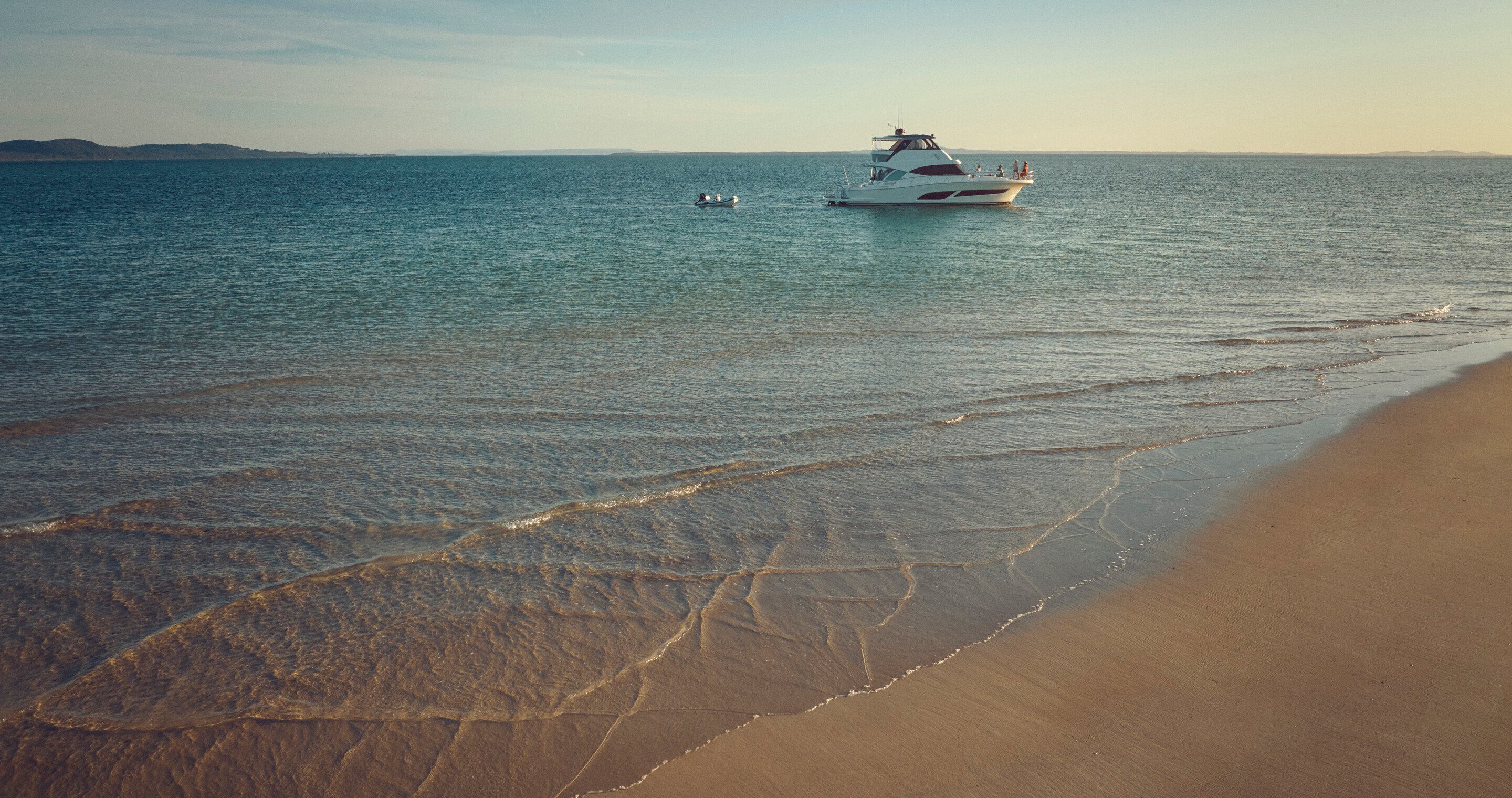 Wide shot of a yacht in the water on a beach