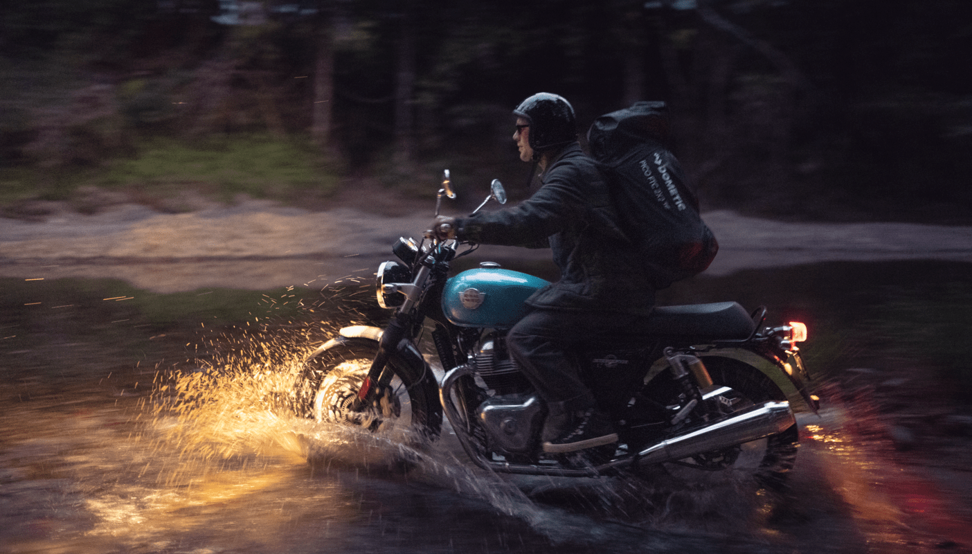 man on motorcycle driving through puddle of water