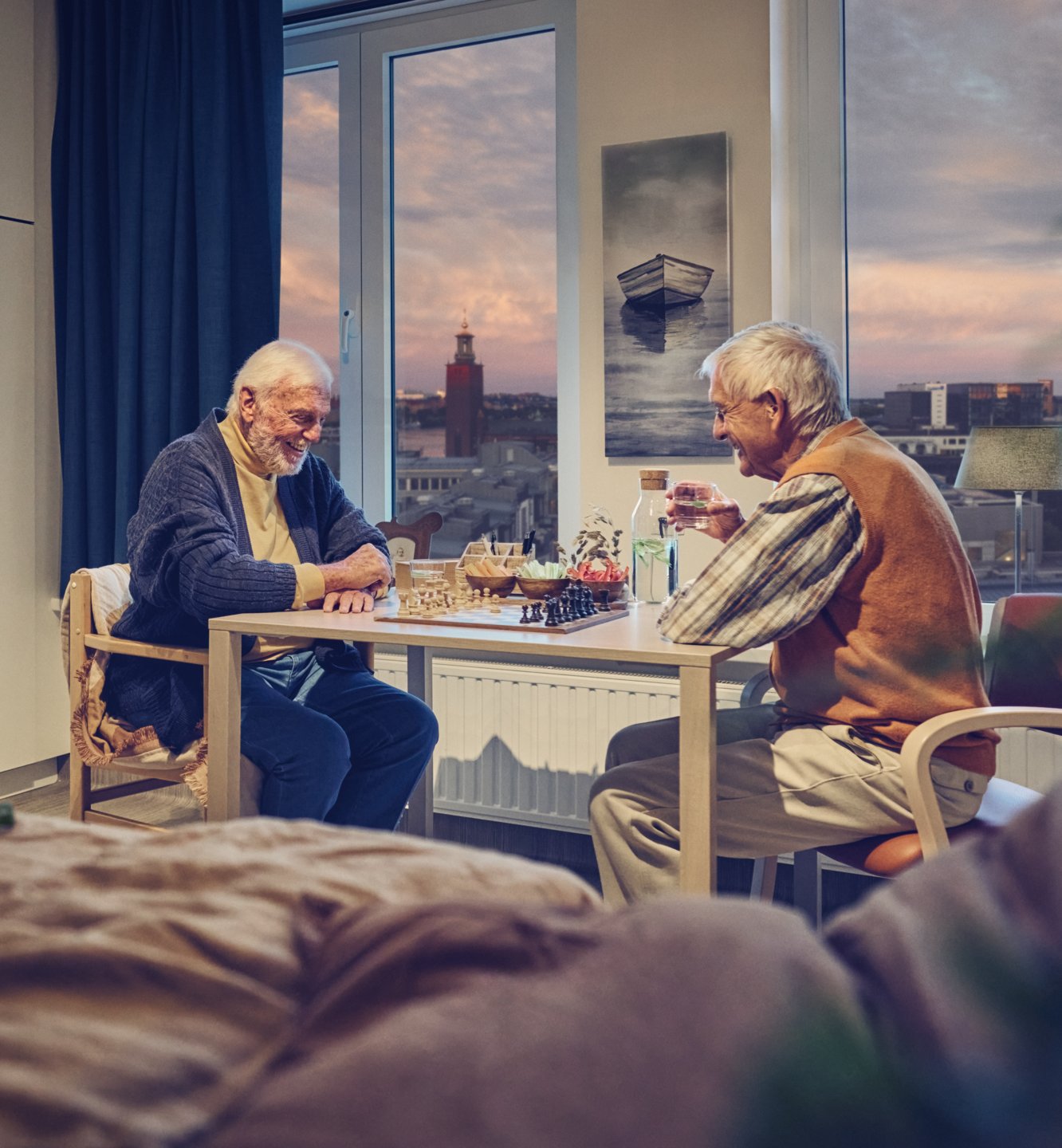 Two elderly gentlemen playing chess and enjoying a conversation.