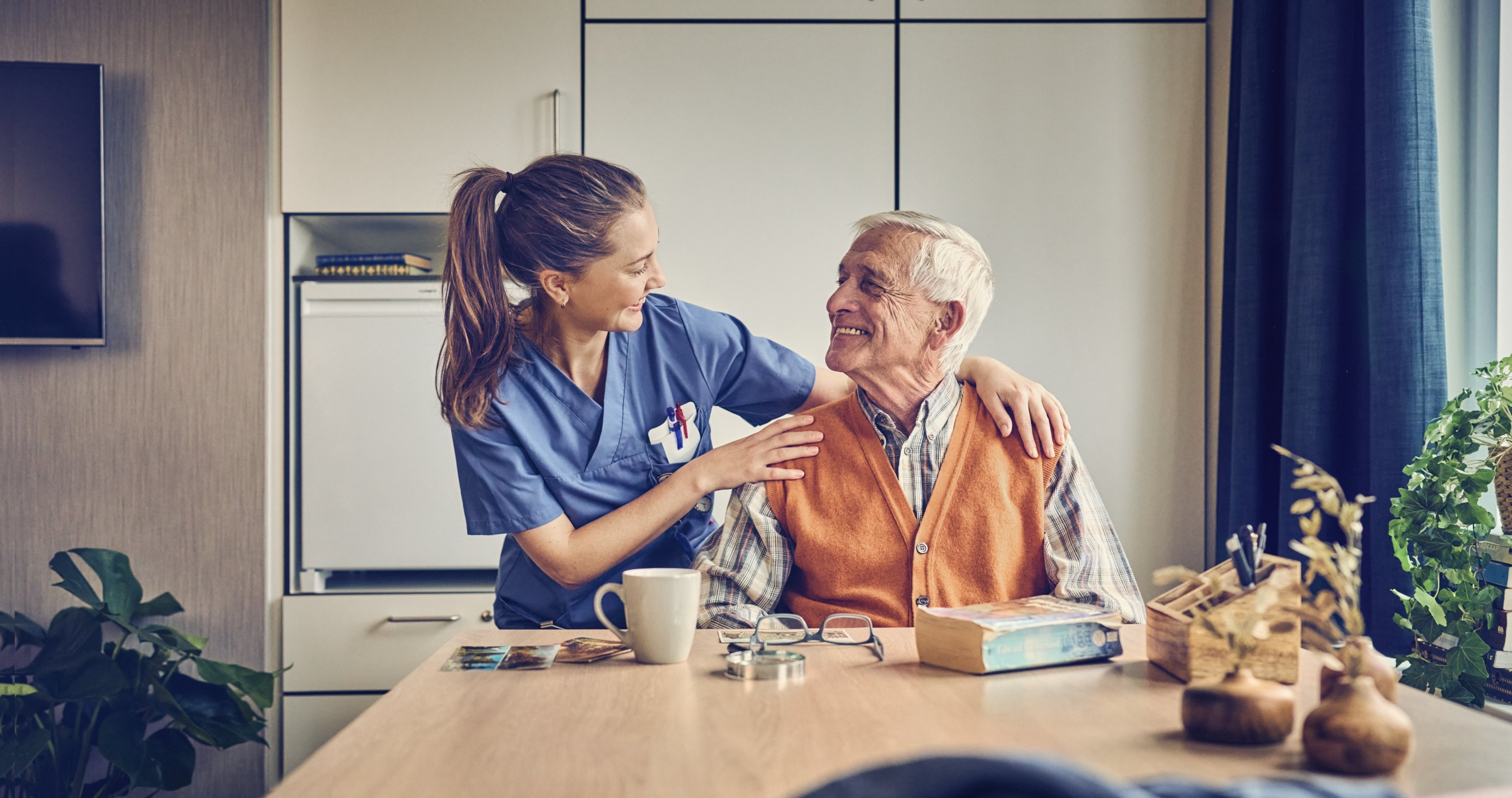 Nurse and elderly man smiling at eachother in a care room