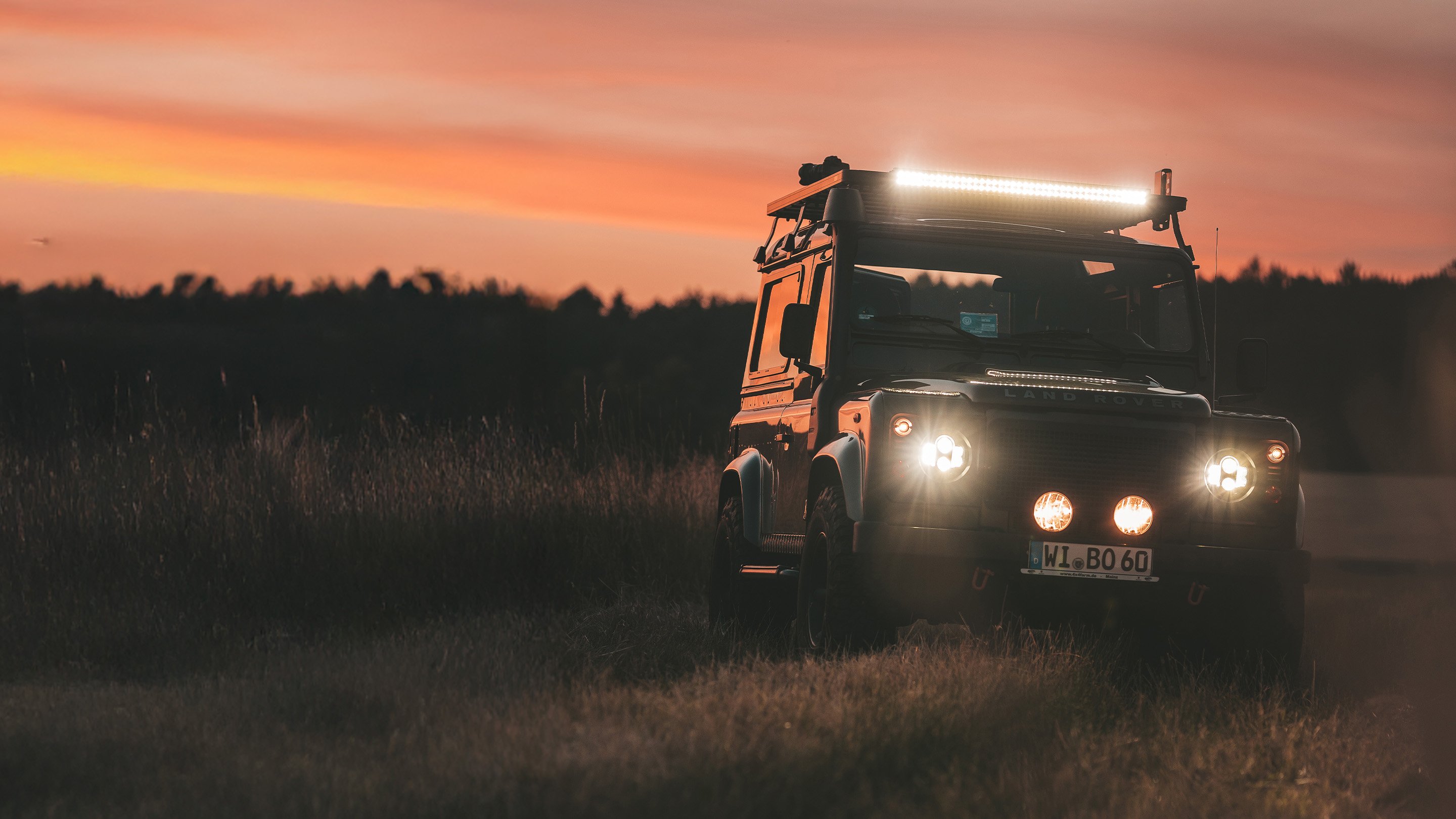Veicolo fuoristrada Land Rover dotato di barra LED Front Runner Dometic, che illumina un percorso al tramonto durante un’avventura overlanding.