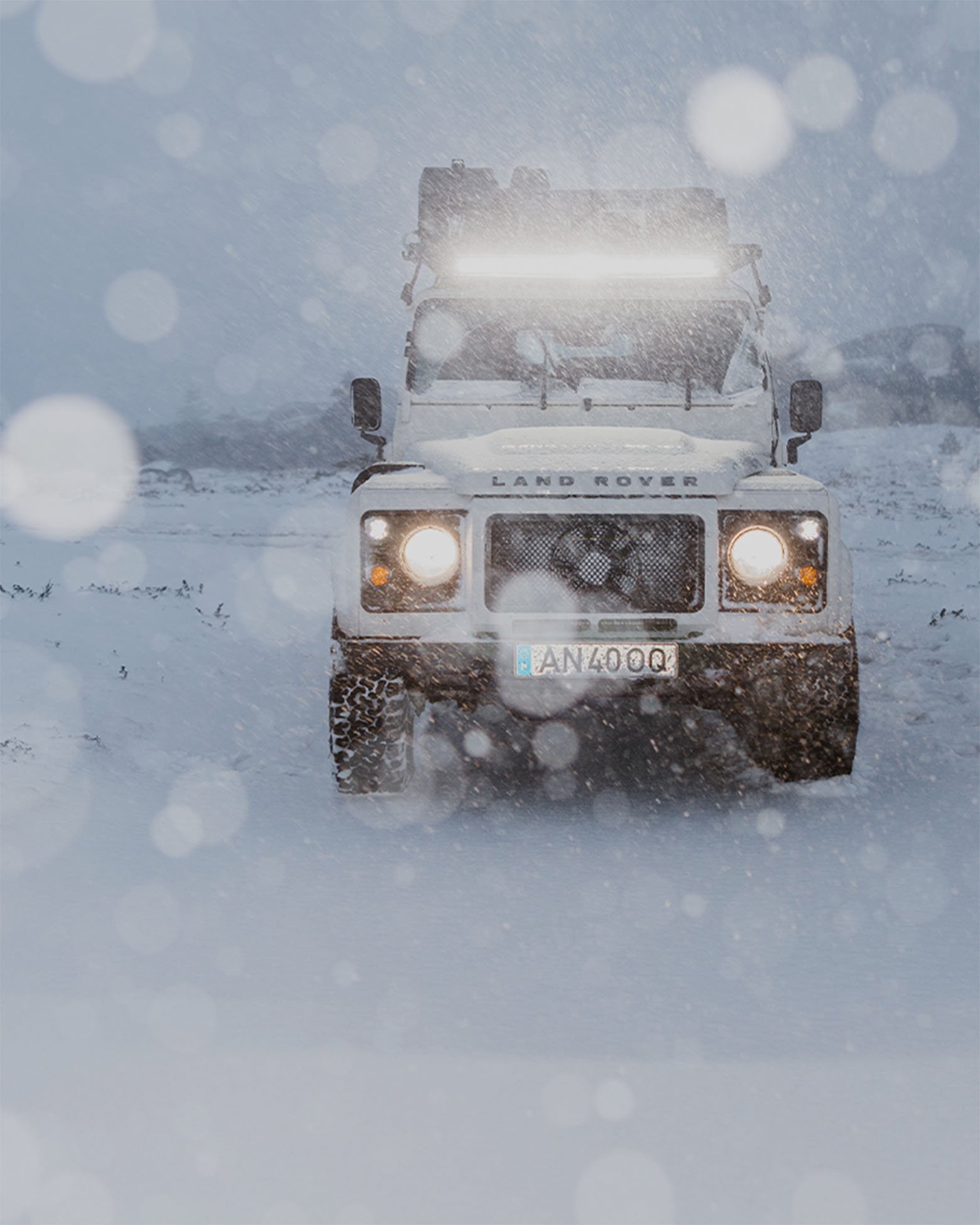 Frontansicht eines Land Rover im Schnee mit Front Runner Dometic LED Light Bar für starke Ausleuchtung bei extremen Winterbedingungen.