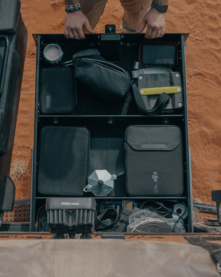 Tiroir de véhicule ouvert contenant outils, équipement de camping et accessoires.