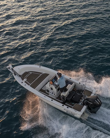 Twee personen op een boot tijdens zonsondergang met een groene Dometic koelbox open op het dek met drankjes erin.