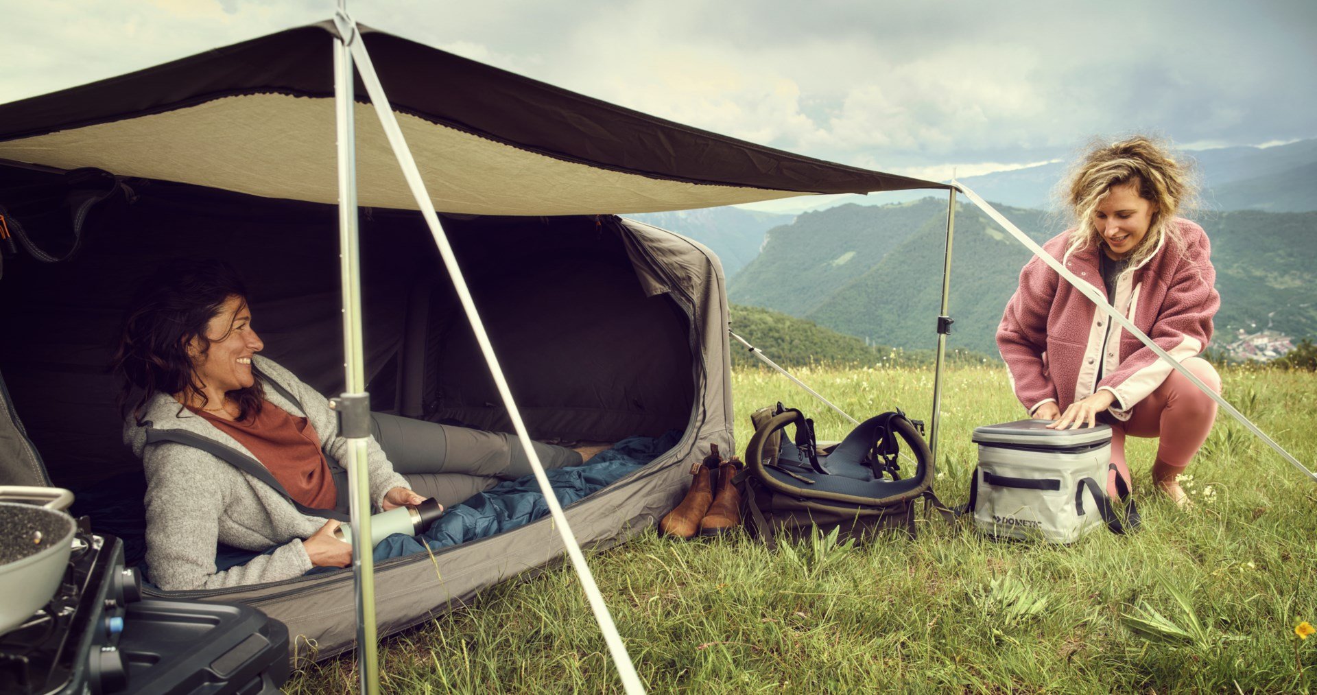 2 women at a campsite in the mountains with an assortment of Dometic products
